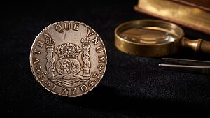 Home reales 14 Moneda De 8 Reales Columnario De Carlos Iii De 1770, Acuñada En Potosí, Junto A Una Lupa Antigua Sobre Fondo Oscuro